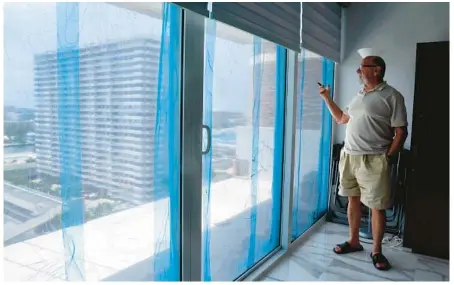  ?? MIKE STOCKER/SOUTH FLORIDA SUN SENTINEL PHOTOS ?? Simon Sherman, in the living room at his 14th floor condo, points out the ongoing constructi­on on his balcony on July 14. He has encountere­d numerous problems with the Condominiu­m Associatio­n of Parker Plaza Estates in Hallandale.