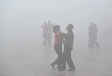  ??  ?? People wearing masks dance amid heavy smog during a polluted day at a square in Fuyang, Anhui province, China in this file photo. — Reuters photo