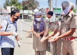  ??  ?? A worker sanitizes the hands of police personnel in Amritsar