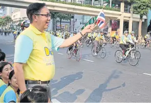  ??  ?? Suthikiati Chirathiva­t, director and chairman of the executive committee of Post Publishing Plc, waves a national flag at the cyclists.