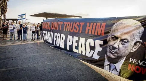  ?? ?? CALL FOR PEACE: Activists in Tel Aviv with a banner portraying premier Benjamin Netanyahu as a warmonger.