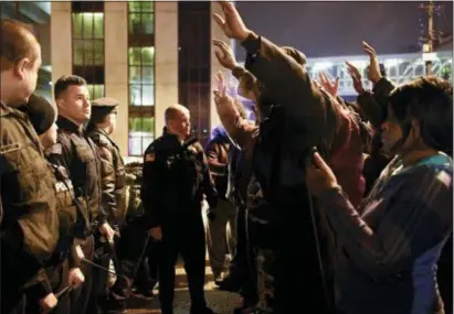  ?? DANIELLE PARHIZKARA­N/THE RECORD VIA AP ?? Protesters raise their hands as they face Paterson police officers during a rally Tuesday in Paterson, in reaction to the death of Jameek Lowery.