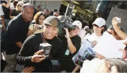  ??  ?? LOS ANGELES: This file photo taken on 29 June 2007 at The Grove shopping center in Los Angeles, California shows John Mariano, 27, surrounded by onlookers and media. Apple celebrates today the 10th anniversar­y of the unveiling of the iPhone, the...