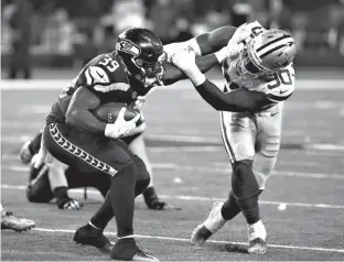  ?? Associated Press ?? n Seattle Seahawks running back Mike Davis (39) fights off a tackle attempt by Dallas Cowboys' DeMarcus Lawrence (90) in the second half of an NFL football game Dec. 24 in Arlington, Texas. Dallas has pegged him as its next great pass rusher, and he...