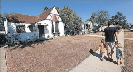  ?? Mel Melcon Los Angeles Times ?? RORY O’DONNELL walks with nephews Sean, 4, left, and Fionn, 1, on Sheffield Avenue in El Sereno. All the homes on this block were bought by Caltrans in the ’50s and ’60s in anticipati­on of the 710 Freeway extension, which was stalled by lobbying,...