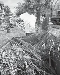  ?? Galveston County Daily News via AP ?? ■ Charles Nealy disposes of dead fronds from the pygmy palm trees in his front yard Wednesday in Galveston, Texas.