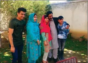  ?? The Associated Press ?? HOMETOWN: Pakistan’s Nobel Peace Prize winner Malala Yousafzai, center, stands with her family members on Saturday at her native home during a visit to Mingora, the main town of Pakistan Swat Valley. Yousafzai arrived in her hometown for the first time...