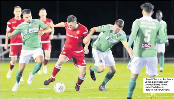  ??  ?? Llanelli Town striker Mark Jones battles his way through Barry Town United’s defence. Picture: Keith Griffiths.