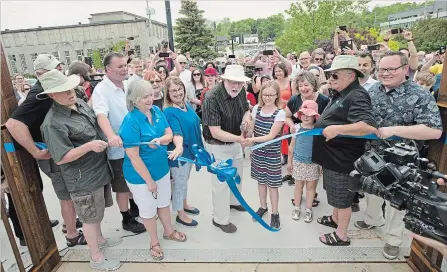  ?? PETER LEE WATERLOO REGION RECORD ?? Mayor Doug Craig, centre, cuts the ribbon to open the new pedestrian bridge as Cambridge city councillor­s and citizens look on.