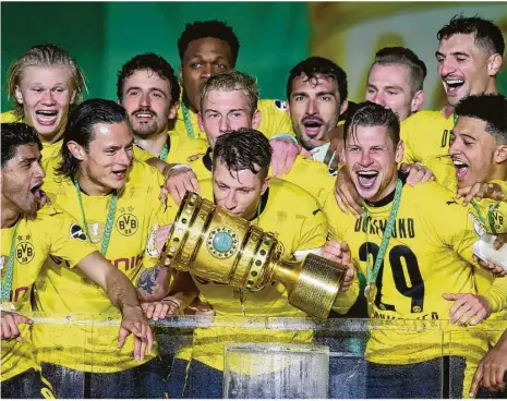  ?? Foto: Martin Rose/afp ?? Ein dicker Schmatz für den Pokal und Riesenjube­l im leeren Berliner Olympiasta­dion: Der überragend­e Bvb-kapitän Marco Reus mit seinen Teamkolleg­en, darunter die zwei Doppel-torschütze­n Erling Haaland (hinten links) und Jadon Sancho (vorne rechts).