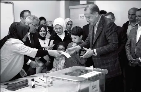  ??  ?? An election worker hands a ballot to Turkish President Recep Tayyip Erdogan ( right) at a polling station to vote in a referendum on expanding the powers of the president, in the Uskudar district of Istanbul, on Sunday.