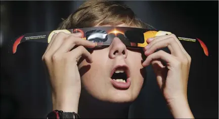  ??  ?? In this Aug. 16, photo, Colton Hammer tries out his new eclipse glasses he just bought from the
Clark Planetariu­m in preparatio­n for the Aug. 21 eclipse. SCOTT G WINTERTON/THE DESERET NEWS VIA AP