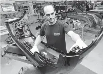  ?? The Associated Press files ?? Christian Baumann carries a car bumper during the opening of a new plant in the Magna Exteriors & Interiors, eastern Germany,