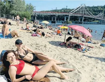  ?? Agèèn Snesn ?? La Júlia i la Valèria, de 21 i 20 anys, prenen el sol a Kíiv en una platja a la vora del Dniéper