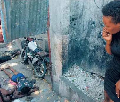  ?? AFP ?? Una mujer observa los cadáveres que yacen en el suelo tras otra noche de violencia en Puerto Príncipe