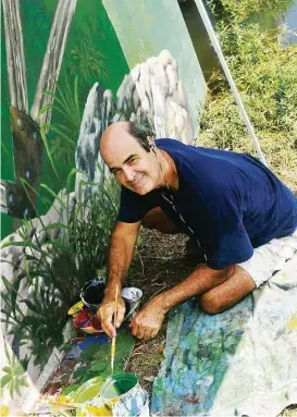  ?? George Wong / For the Chronicle ?? Artist Larry Crawford works in the hot part of the day to create a mural on an embankment mural on the Westchase District Library Loop Trail near the Robinson-Westchase Neighborho­od Library.