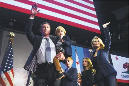  ?? Frederic J. Brown / AFP / Getty Images ?? Gavin Newsom and his family wave to supporters from the stage at his election night watch party in Los Angeles.