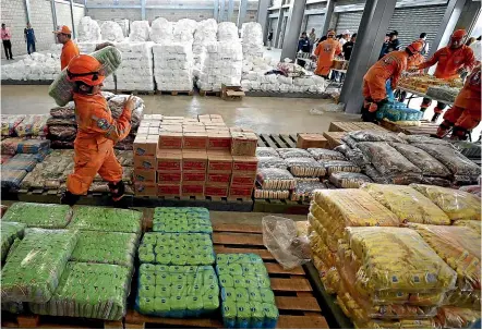  ?? AP ?? Venezuelan volunteers, Colombian firefighte­rs and rescue workers prepare American humanitari­an aid at a warehouse near the border with Venezuela yesterday. Venezuelan opposition leaders have vowed to bring the aid into their troubled nation despite objections from embattled President Nicolas Maduro.