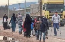  ??  ?? People walk to a temporary housing complex near the border gate in Kilis, Turkey. “We are providing them with humanitari­an support,” said Deputy Prime Minister Numan Kurtulmus.
CHRIS MCGRATH, GETTY IMAGES