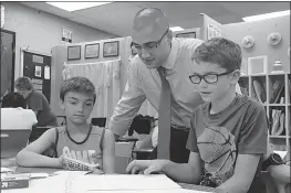  ??  ?? Dr. James Craik Elementary School third graders Kilian Rupard, left, and Jackson Donnick go over a recent lesson with Vice Principal Benjamin Harrington. Harrington was named Charles County Public Schools Vice Principal of the Year.