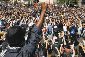  ?? John Minchillo / Associated Press ?? Protesters unite with arms raised in Minneapoli­s, where racial tension erupted after a black man died in police custody when a white officer pressed a knee on his neck for eight minutes.