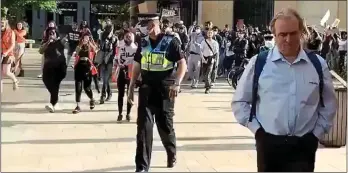  ??  ?? FOCUS OF THE FURY: Images from a film shared on Twitter showing Peter Hitchens walking calmly on as baying demonstrat­ors, gathered to protest against a statue of Cecil Rhodes, follow him