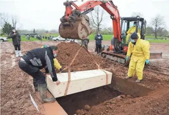  ??  ?? A casket is lowered into a grave at the Mount Richmond Cemetery. About 360 people are buried at the cemetery each year. More than 130 were buried in the first three weeks of April alone.