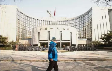  ??  ?? Major overhaul: A pedestrian walking past the PBoC headquarte­rs in Beijing. A new regulatory structure with the central bank as the pivot is emerging as the annual legislativ­e meetings progress through their second week. — Bloomberg