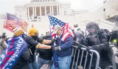 ?? JOHN MINCHILLO/AP ?? Rioters loyal to President Donald Trump try to break through a police barrier on Jan. 6, 2021, at the U.S. Capitol.