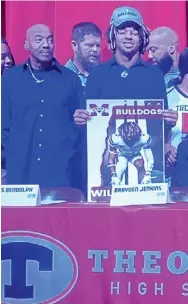  ?? ?? Theodore (Alabama) cornerback Will James holds up a Mississipp­i State banner after signing with the Bulldogs on Wednesday. (Photo by Brett Greenberg, for Starkville Daily News)