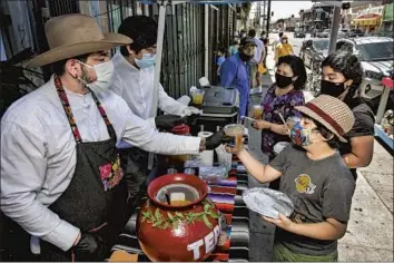  ?? Photograph­s by Irfan Khan Los Angeles Times ?? ALEX LOPEZ, left, and his 17-year-old son distribute tepache, a fermented pineapple drink, for free at Mid-City Cookouts on Saturday in front of flower and clothing store Yeaj Yalhalhj in Arlington Heights.