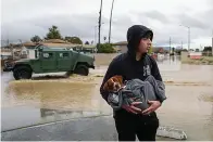  ?? AP, File) ?? Esteban Sepulveda holds his dog Milo while leaving his home in Pajaro Valley, Calif., March 12, 2023. Record snowfall and rain have helped to loosen drought’s grip on parts of the western U.S. as national forecaster­s and climate experts warned Thursday, March 16, that some areas should expect more flooding as the snow begins to melt. (Shae Hammond/Bay Area News Group via