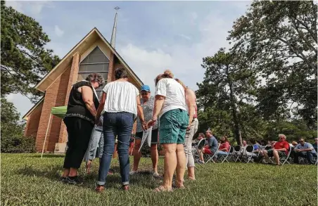  ?? Steve Gonzales photos / Houston Chronicle ?? Pastor Kathy Sebring, left, leads church elders in prayer before the start of a worship service on the front lawn of the First Presbyteri­an Church of Dickinson on Sunday. The only thing that wasn’t damaged at the church by Hurricane Harvey was the...