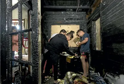  ?? PHOTO: ALDEN WILLIAMS/STUFF ?? The Abundo family had their Addington home damaged by fire on Saturday morning. Aquila, 8, left, watches as her siblings go through the damaged bedroom.