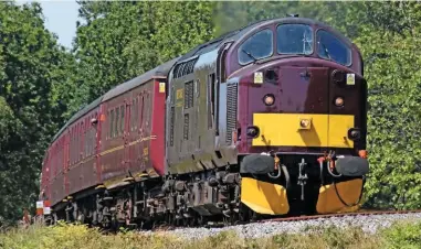  ?? MARK PIKE. ?? West Coast Railway 37518 leads one of the early Swanage Railway trial trains through Creech Bottom (near Wareham) on June 14. The railway hired Class 33s, ‘37s’ and stock from WCR in the early part of the trial.