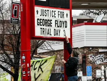  ?? Chandan Khanna/AFP via Getty Images ?? A man in Minneapoli­s on Wednesday changes the number on a sign at a makeshift memorial for George Floyd before the third day of jury selection began in the trial of former Minneapoli­s police Officer Derek Chauvin, who is accused of killing Floyd.