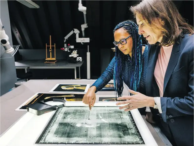  ?? PHOTOS: MICHEL DE GROOT / THE NEW YORK TIMES ?? Abbie Vandivere, left, the paintings conservato­r at the Mauritshui­s Royal Picture Gallery, and museum director Emilie Gordenker examine an X-ray photo of Johannes Vermeer’s 1665 masterpiec­e Girl With a Pearl Earring in The Hague.