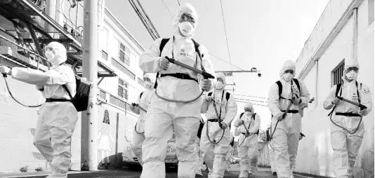  ?? AP ?? South Korean soldiers wearing protective gear spray disinfecta­nt as a precaution against the novel coronaviru­s on a street in Gyeongan on Wednesday.