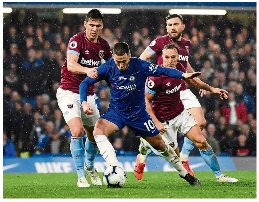  ??  ?? Slick: Chelsea’s Eden Hazard (centre) wriggles his way past West Ham players during the Premier League match at Stamford Bridge on Monday. — Reuters