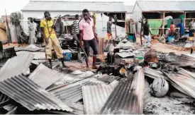  ??  ?? MAIDUGURI: This file photo taken on June 8, 2017 shows armed members of a local defense group inspecting the damage of a suicide blast. — AFP