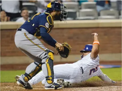  ?? AP ?? The Mets’ Dominic Smith slides past Brewers catcher Omar Narvaez to score on a double by Pete Alonso in the seventh inning.