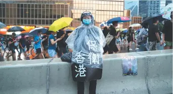  ??  ?? Un manifestan­t porte un habit de pluie sous lequel est inscrit «Protéger Hong Kong», lors d’une marche, dimanche, à Hong Kong. - Associated Press: Kin Cheung