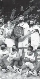  ?? GAZETTE PAUL W. GILLESPIE | CAPITAL ?? Navy players pose with the Alumni Trophy after beating archrival Army, 69-62, Saturday afternoon.