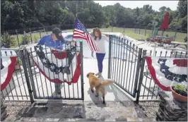  ?? STAN CARROLL/ THE COMMERCIAL APPEAL ?? “This is a time to celebrate our independen­ce and the freedoms we enjoy,” said John Caldwell, hanging bunting with his future daughter-in-law Melissa Turner and dog Shiloh.