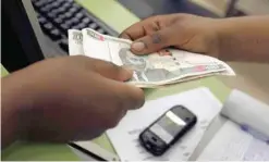  ?? — AFP ?? A customer conducts a mobile money transfer inside the Safaricom mobile phone care centre in the central business district of Kenya’s capital Nairobi.