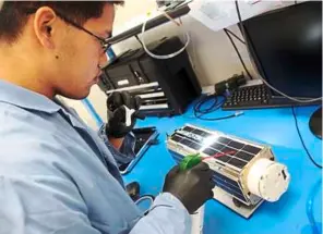  ??  ?? Mechanical engineer alexander Wen working on a satellite camera called dove at Planet Labs, a privately-funded company in San Francisco. dozens of the small breadbox-sized devices were sent to the Internatio­nal Space Station for eventual deployment. –...