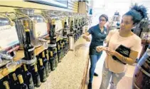  ?? JOE BURBANK/STAFF PHOTOGRAPH­ER ?? Sales associate Gracie Jones, left, assists shopper Kaity Etchison while she samples olive oils and balsamic vinegars at The Sacred Olive.