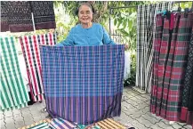  ??  ?? A villager shows pha kao ma, a chequered loincloth, woven by locals.