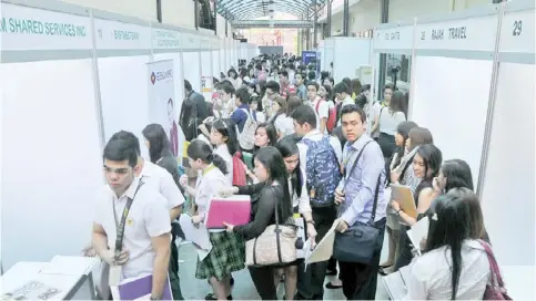  ??  ?? Fresh graduates and other young applicants line up in front of kiosks of prospectiv­e employers at a job fair in Manila.