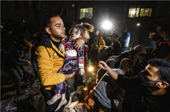  ?? MAHMUD HAMS/AFP VIA GETTY IMAGES ?? A man carried a young victim after being removed from under the rubble of a building hit in Rafah Thursday.